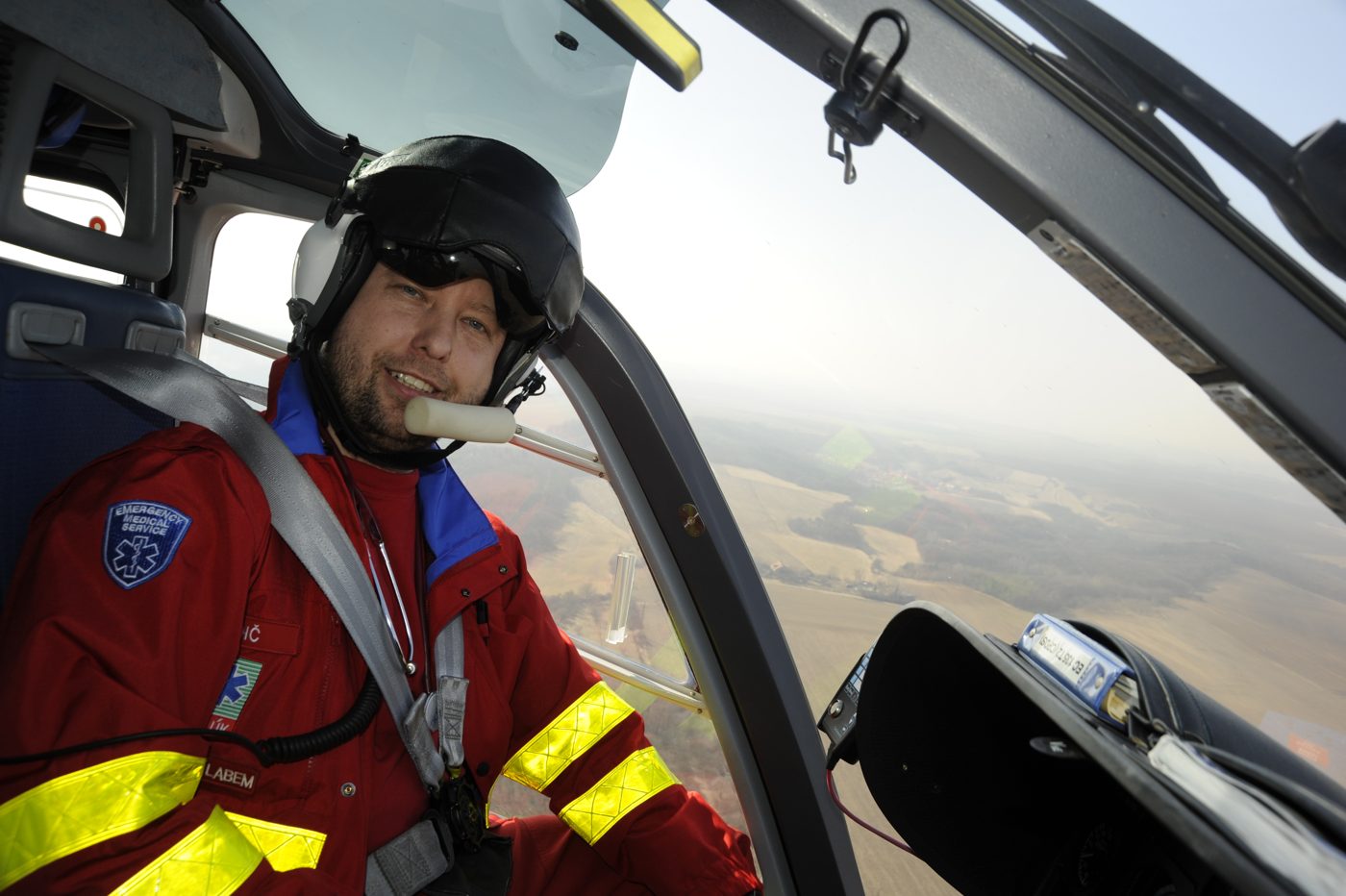In the cockpit of a rescue helicopter, wearing a flight suit and helmet